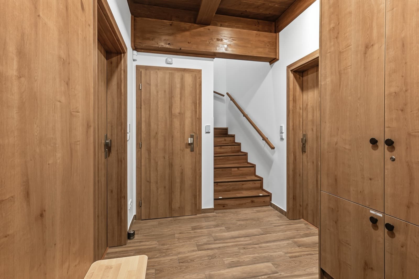 Vstupní chodba s dřevěným schodištěm a bezklíčovým vstupem na PIN do apartmánů
